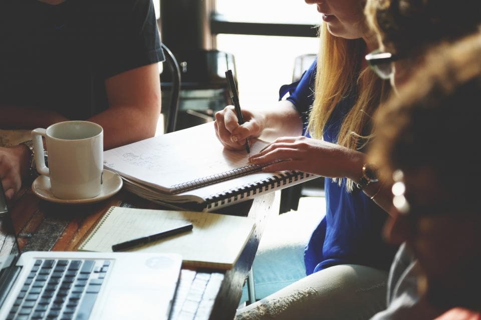 Несколько человек обсуждают работу за столом с ноутбуками